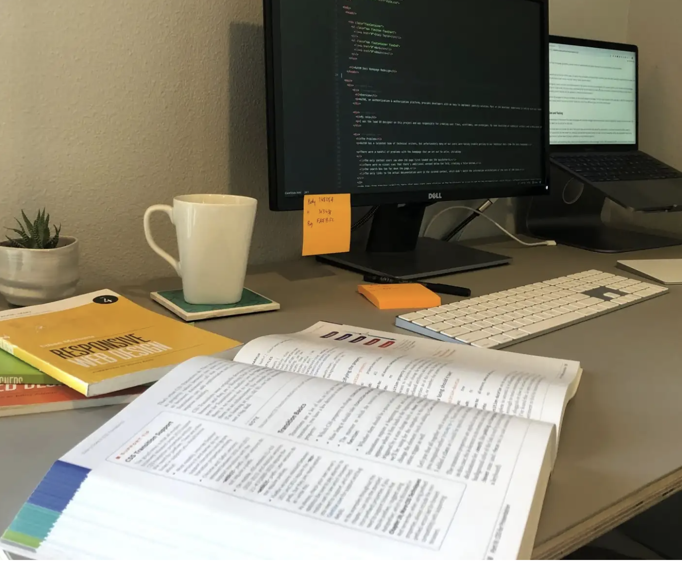 A desk piled with web design books and a computer screen showing a code editor.